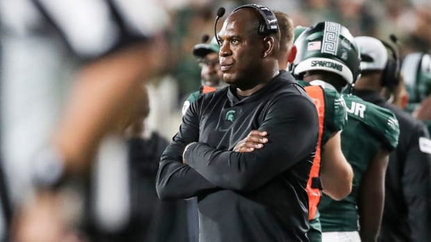 Mel Tucker stands with a headset on and his arms crossed on his chest